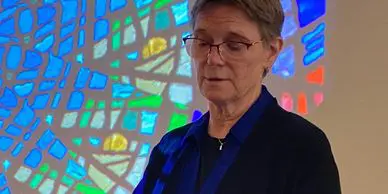 Individual speaking in front of stained glass.