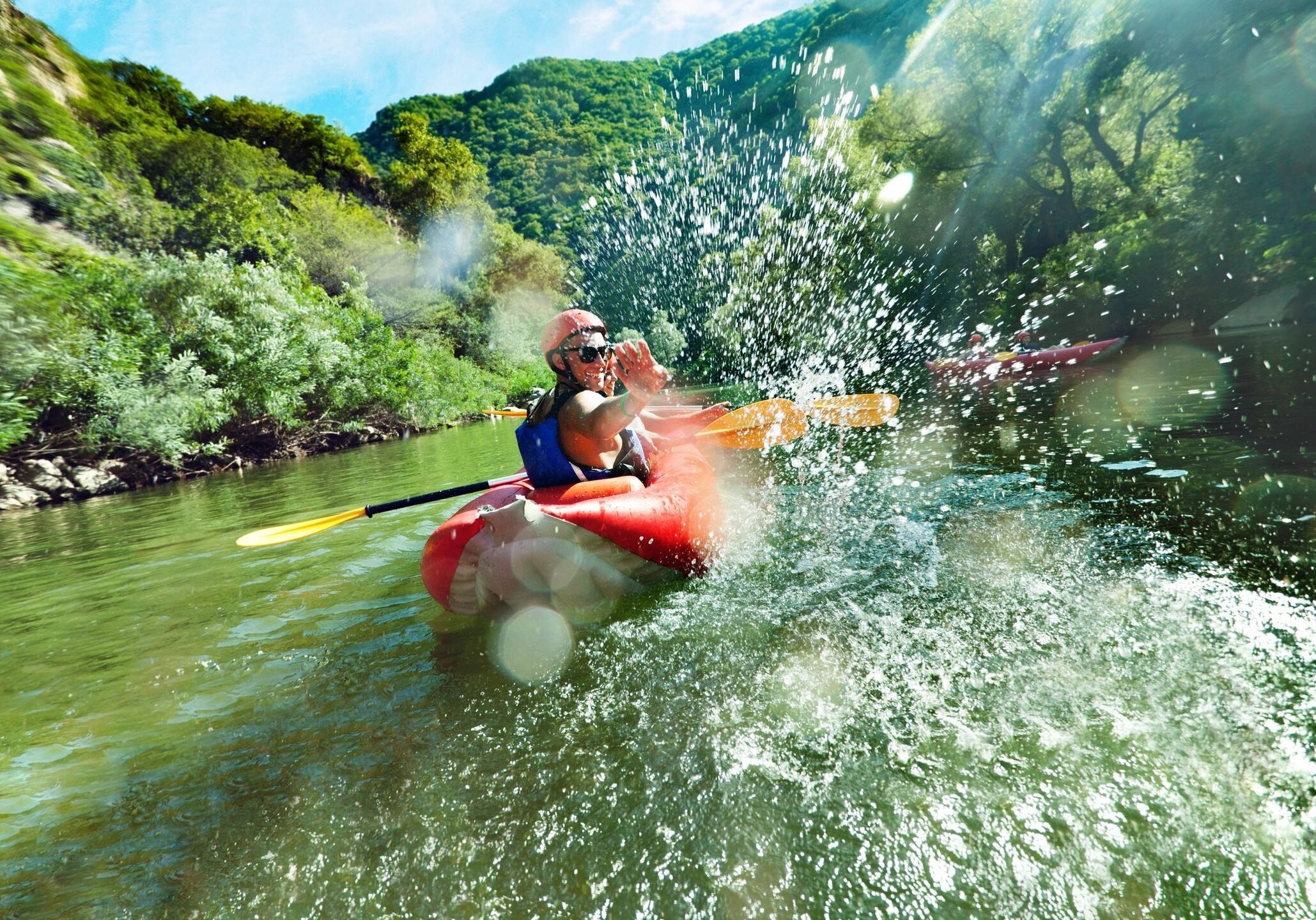 Kayaker splashing through river rapids